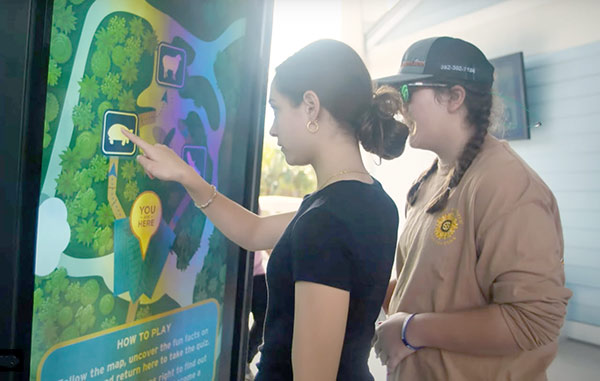 Girl touching The The TV Shield PRO Touch outdoor interactive touch screen at TECO Clean Energy Center