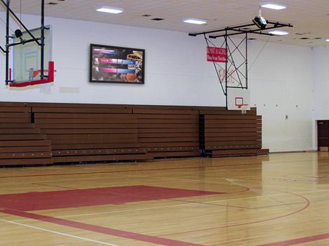 A gym with The TV Shield Pro Lite outdoor TV enclosure, displaying the score and team details 